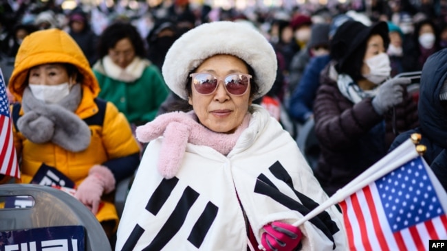 Para pendukung Presiden Korea Selatan Yoon Suk Yeol menghadiri pawai di dekat gedung Mahkamah Konstitusi di Seoul, Kamis, 23 Januari 2025, setelah Yoon tiba untuk persidangan. (Foto: Anthony Wallace/AFP)