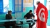 FILE - A Tunisian draped in the national flag arrives at a polling station to vote in La Marsa, outskirts of Tunis, Tunisia, Dec, 21, 2014.