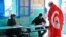 FILE - A Tunisian draped in the national flag arrives at a polling station to vote in La Marsa, outskirts of Tunis, Tunisia, Dec, 21, 2014.