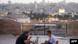 Palestinos se reúnen para romper su ayuno durante el mes sagrado musulmán del Ramadán, en el Monte de los Olivos con el telón de fondo de la Ciudad Vieja de Jerusalén y el recinto cerrado de la Mezquita al-Aqsa.