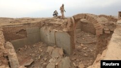 A member of the Iraqi army walks around the remains of wall panels and colossal statues of winged bulls, destroyed by Islamic State militants in the Assyrian city of Nimrud, south of Mosul, Iraq, Nov. 16, 2016. 