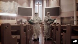 Public officials disinfect pews as a precaution against the coronavirus at the Yoido Full Gospel Church in Seoul, South Korea.