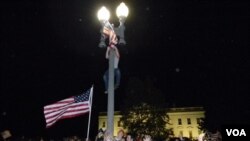 La multitud se reunió a celebrar frente a la Casa Blanca, donde algunos intrépidos se subieron a las columnas de luz para elevar la bandera más alto.