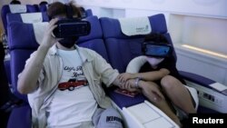 Seorang anak perempuan dan ayahnya menggunakan alat realitas virtual (VR) untuk merasakan naik pesawat dan tur ke berbagai kota di kala pandemi melanda di Tokyo, Jepang (REUTERS/Kim Kyung-Hoon)