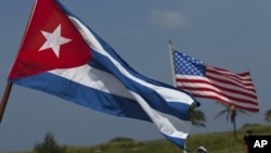 La gente de un club náutico local lleva las banderas cubana y estadounidense a la costa para mirar a la nadadora estadounidense Diana Nyad, el 18 de agosto de 2012.