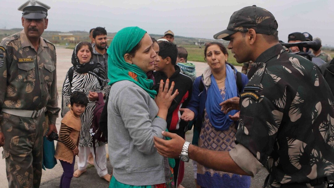 A Kashmiri flood victim, center, pleads to an Indian army officer to rescue her family members after she was airlifted by the army from her flooded neighborhood to the Indian Air Force base in Srinagar, Sept. 8, 2014. 