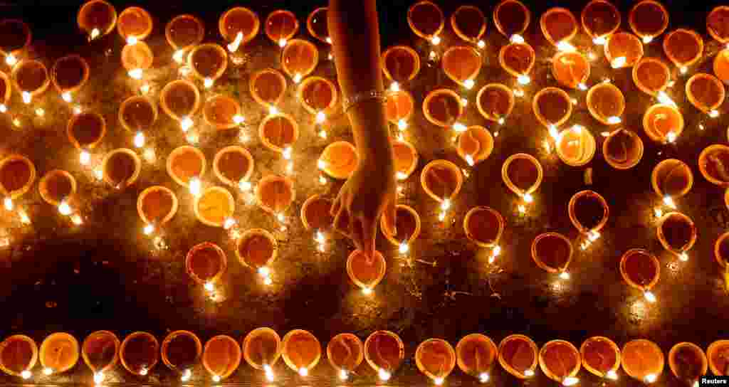 A devotee lights oil lamps at a religious ceremony during the Diwali festival at a Hindu temple in Colombo, Sri Lanka.