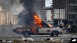 Un auto es envuelto por las llamas durante una manifestación en Caracas, el jueves 20 de julio.