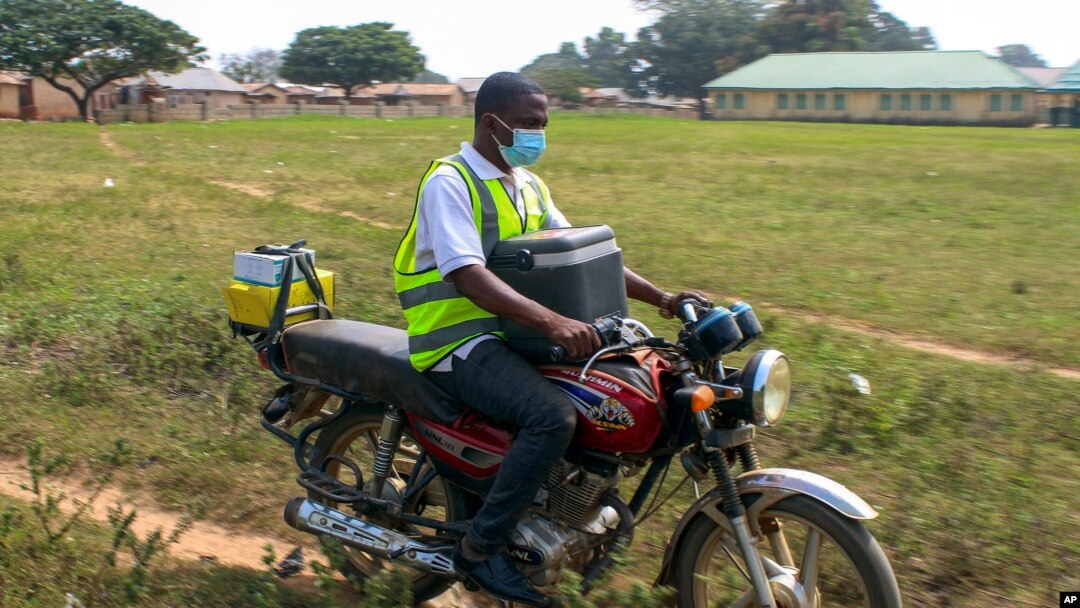 FILE - Yunusa Bawa, a community health worker, rides on a motorbike with a box of AstraZeneca coronavirus vaccines, in Sabon Kuje on the outskirts of Abuja, Nigeria, Dec 6, 2021.