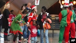 Flight attendant Dre Zulaica, front left, greets a participant and her guardian during the United Airlines annual "fantasy flight" to a fictional North Pole at Denver International Airport, in Denver, Colorado, Dec. 14, 2024.