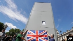 Members of far-right Football Lads Alliance hold a British flag in front of a protective covering surrounding the statue of former British Prime Minister Sir Winston Churchill in Parliament Square, central London, June 13, 2020.