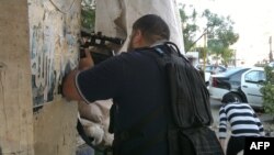 An armed militiaman stands behind a barricade of sandbags in Tripoli's Sunni Muslim neighborhood of Bab al-Tabbaneh June 2, 2012. 