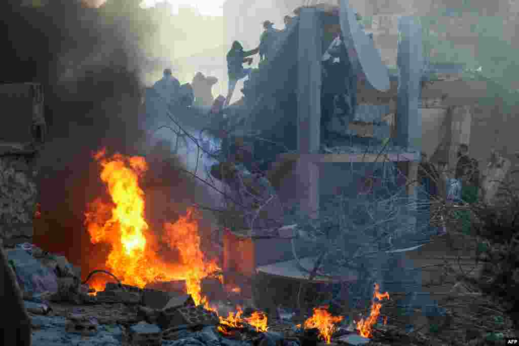 People and rescuers try to put out a fire at the site of an Israeli airstrike that targeted a densely populated neighborhood in Lebanon&#39;s eastern city of Baalbek.