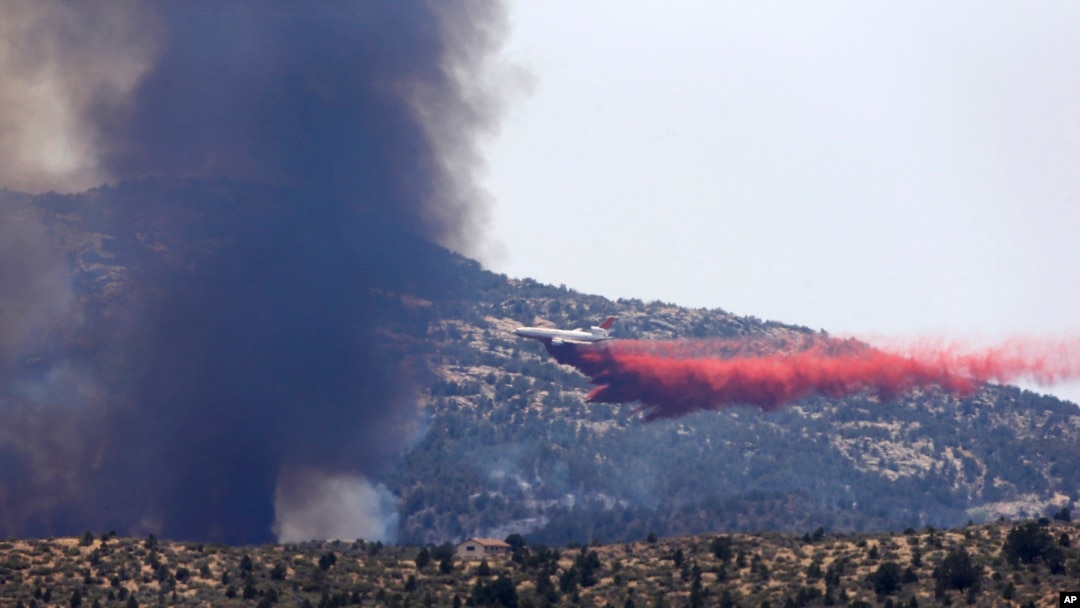 Pesawat militer bertangki air menyiramkan air ke titik-titik api guna mengekang kebakaran di kota Yarnell, Arizona (1/7). 