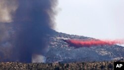 Pesawat militer bertangki air menyiramkan air ke titik-titik api guna mengekang kebakaran di kota Yarnell, Arizona (1/7). 