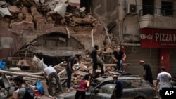 People remove debris from a house damaged by Tuesday's explosion in the seaport of Beirut, Lebanon, Aug. 7, 2020. 