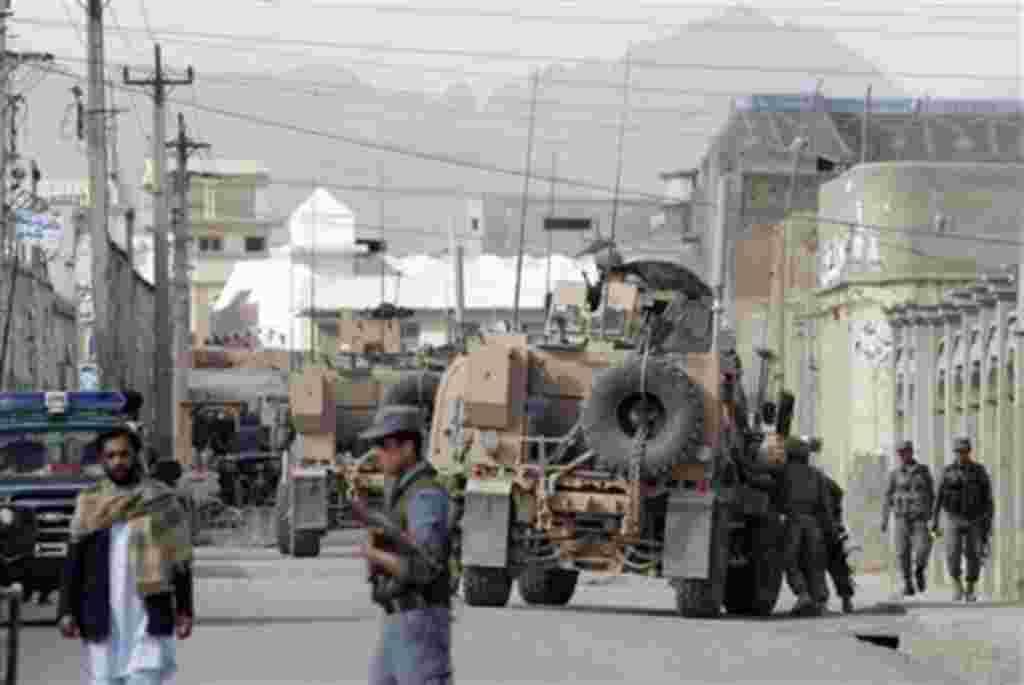 Afghan and NATO forces secure the entrance of the police headquarters after a Taliban suicide attack killed the police chief of southern Afghanistan's Kandahar province, Khan Mohammad Mujahid and his two bodyguards, in Kandahar, Afghanistan, Friday April 