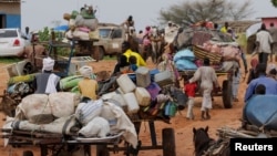 FILE - Chadian cart owners transport belongings of Sudanese people who fled the conflict in Sudan's Darfur region, while crossing the border between Sudan and Chad in Adre, Chad, on Aug. 4, 2023.