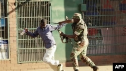 Un soldat zimbabwéen bat un homme pendant les protestations éclatées à la suite des allégations des fraudes électorales, dans une rue de Harare, le 1er août 2018.