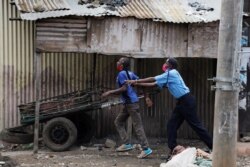 FILE - A police officer prods a man at a checkpoint during lockdown in the Eastleigh neighborhood of Nairobi, Kenya, May 7, 2020.