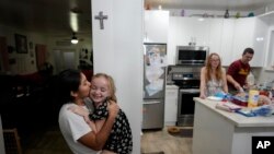 Sol, argentina de 14 años, besa a Maddie Hazelton mientras juegan en la cocina de los padres que acogieron a Sol, Andy y Caroline Hazelton en Homestead, Florida, el 18 de diciembre de 2023. 