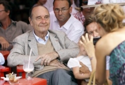 FILE - France's former President Jacques Chirac poses as a womans takes a picture of him sitting at a table outside the famous Le Senequier cafe in the French Riviera searesort of Saint-Tropez, Aug. 14, 2011.