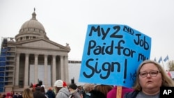 Melissa Knight, qui enseigne l'art au collège d'Ardmore, dans l'Oklahoma, tient une pancarte à l'occasion du rassemblement des enseignants au State Capitol à Oklahoma City, le lundi 2 avril 2018, pour protester contre le manque de financement des écoles. 