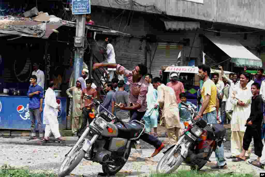 A supporter of Pakistan&#39;s ruling party throws a rock at the procession of cricketer-turned-politician Imran Khan in Gujranwala, Pakistan, Aug. 15, 2014.