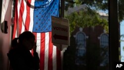 ARCHIVO - Un trabajador electoral espera para saludar a los votantes anticipados en Alexandria, Virginia, el lunes 26 de septiembre de 2022.