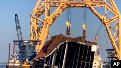 FILE - A towering crane straddles the capsized cargo ship Golden Ray, its interior decks exposed after the ship's bow was cut off and hauled away, off the coast of St. Simons Island, Ga., Feb. 25, 2021. 