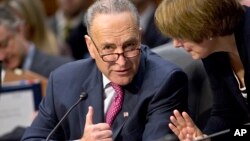 El senador Chuck Schumer consulta con una colega sobre las enmiendas a la reforma migratoria.