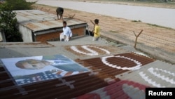 People display portraits of U.S. President Barack Obama on the roof of their houses near Phnom Penh Airport November 14, 2012. Around 182 families living around the airport have been served with eviction notices ahead of Obama's historic visit to the country.