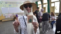 A voter poses for a photo with her inked finger after casting her ballot inside a polling station during the presidential elections in Algiers, Algeria, Sept. 7, 2024.