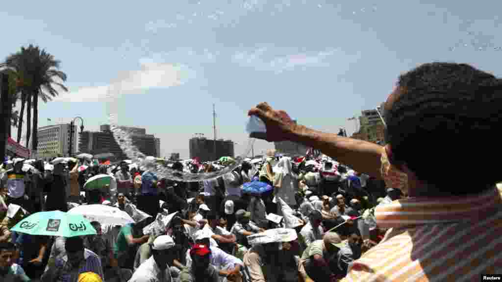 A supporter of the Muslim Brotherhood cools fellow supporters with water.