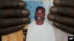 FILE: FILE - In this Feb. 5, 2010 file photo, shopkeeper Ousmane Diallo displays a photo of his son Madieye Diallo, a gay activist whose body was disinterred and desecrated hours after burial, in Thies, Senegal.
