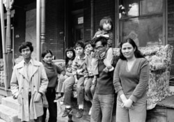 FILE - Nou Moeur, a Cambodian refugee, carries his daughter on his shoulders as his wife, Orrin, right, and his children, and brother Nou Samean, sister Nou Yat, rear, are shown outside their row home in Harrisburg, Pa., March 17, 1983.
