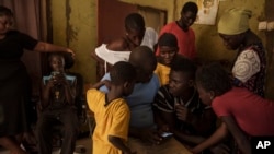 Papa Dieye, de 19 años, centro derecha, habla con su padre, Badara Dieye, mientras miran fotografías de su rescate en un teléfono celular, rodeado de otros familiares en Diogo, Senegal, el lunes 28 de agosto de 2023.