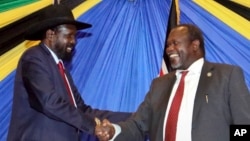 FILE - South Sudan's President Salva Kiir, left, shakes hands with rebel leader and former vice president Riek Machar after signing an agreement to reunify their political party in Arusha, Tanzania, Jan. 21, 2015. 