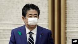 FILE - Wearing a protective mask, Japanese Prime Minister Shinzo Abe leaves a news conference at the prime minister's official residence in Tokyo, April 17, 2020.