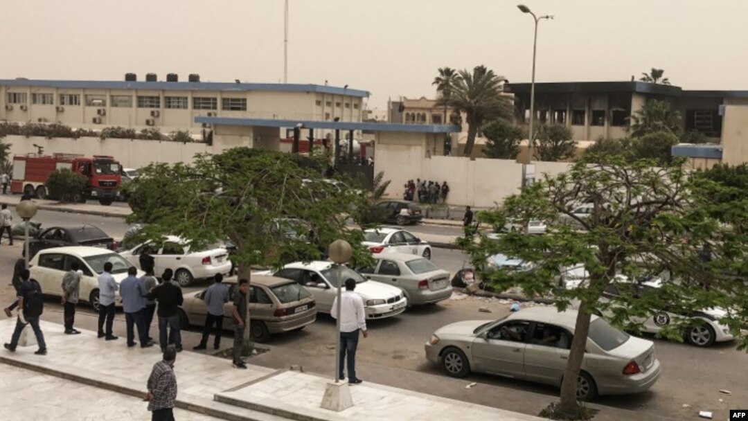 Orang-orang berkumpul di luar markas komisi pemilihan Libya di ibukota Tripoli setelah menjadi target serangan bunuh diri yang menewaskan sedikitnya 11 orang menurut pihak berwenang dan saksi mata, 2 Mei 2018. (AFP PHOTO / Mahmud TURKIA)