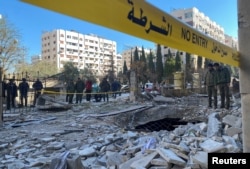 Petugas polisi berdiri di atas puing-puing bangunan yang rusak di lokasi serangan roket, di lingkungan Kafr Sousa, Damaskus tengah, Suriah, 19 Februari 2023. (Foto: REUTERS/Firas Makdessi)