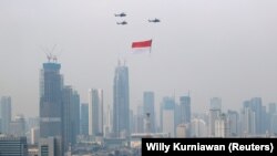 Indonesian Air Force helicopters carrying a big flag fly above high rise buildings during the country's 76th Independence Day celebrations.