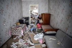 A woman stands inside her damaged house two days after shelling by Armenian's artillery during fighting over the separatist region of Nagorno-Karabakh, in Ganja, Azerbaijan, Oct. 13, 2020.