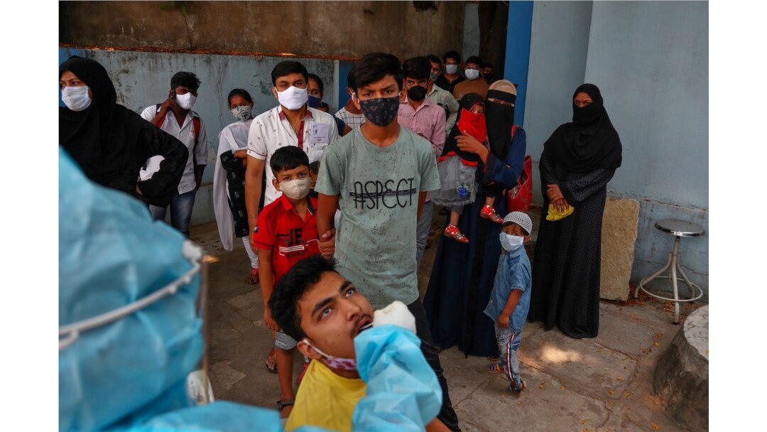 A health worker takes a nasal swab sample of a man to test for COVID-19 as others wait their turn to get tested at a hospital in Hyderabad, India, April 19, 2021.