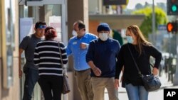 Customers, wearing masks, wait their turn to enter a bank in Los Angeles, Califiornia, April 3, 2020. 