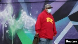 Un hombre en California camina por la calle usando su mascarilla, para prevenir el contagio por coronavirus. 