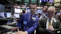 Specialist Christopher Culhane, left, works at his post on the floor of the New York Stock Exchange Tuesday, Oct. 4, 2011. (AP Photo/Richard Drew)