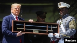 Ketua Kadet Angkatan 2020 West Point, Joshua Phillips, memberikan cindera mata pedang kepada Presiden Donald Trump saat wisuda di Akademi Militer AS, West Point, di New York, 13 Juni 2020. (Foto: Reuters)