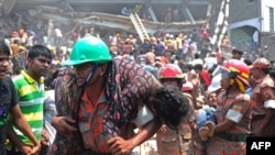 Yon ponpye ap pote yon anplwaye izin fabrikasyon rad ki blese apre bilding nan fin tonbe nan katye Savar, tou pre Daka (24 avril 2013).