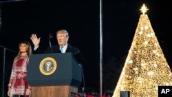 President Donald Trump, with first lady Melania Trump, waves during the National Christmas Tree lighting ceremony at the Ellipse near the White House in Washington, Dec. 5, 2019. 